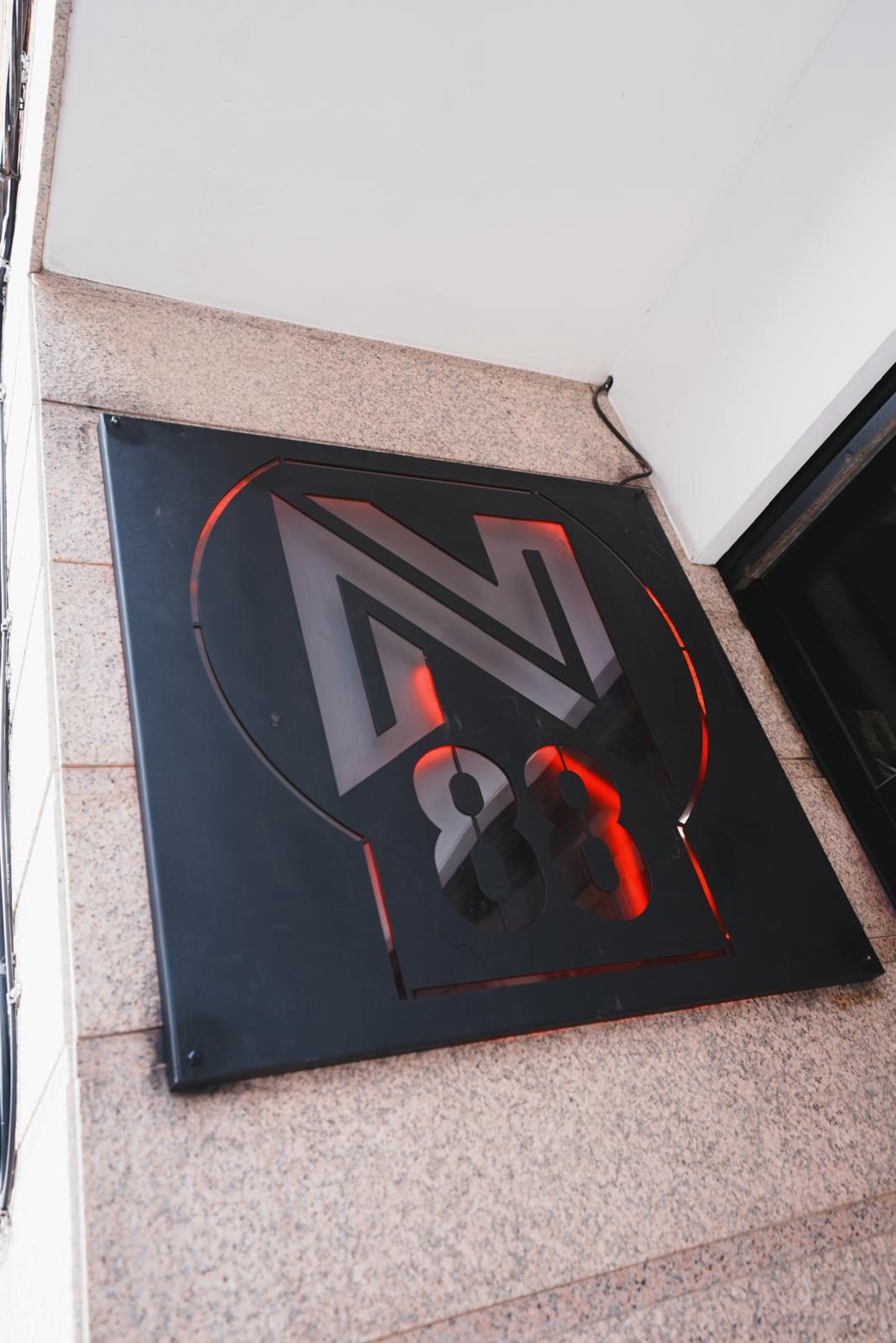 Rótulo de N88GYM iluminado en rojo en la fachada de C/ Les Colomeres 145