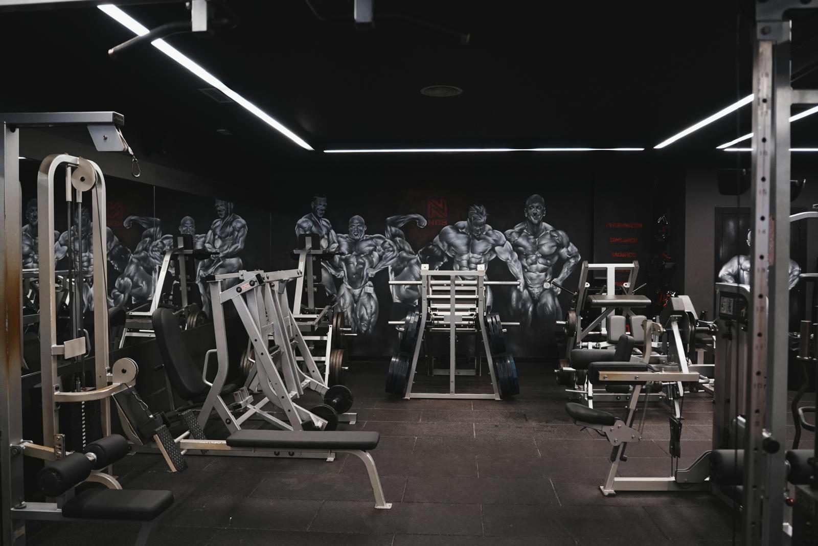 Sala de musculación de N88GYM con máquinas y el mural de culturistas