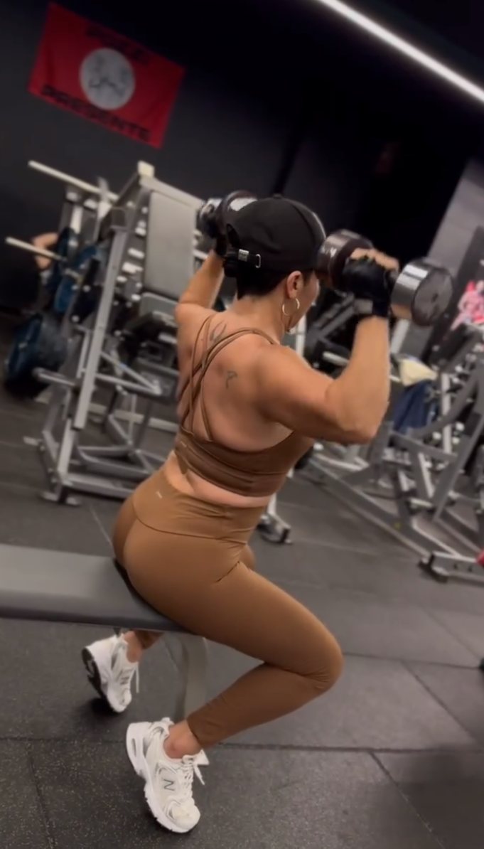 Socia de N88GYM haciendo press de hombro con mancuernas